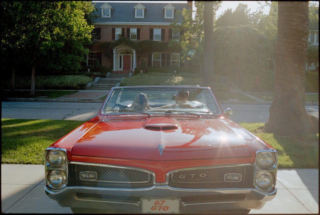 couple backing out of driveway in a red convertible