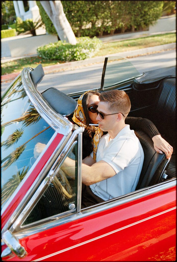Couple kissing in red convertible