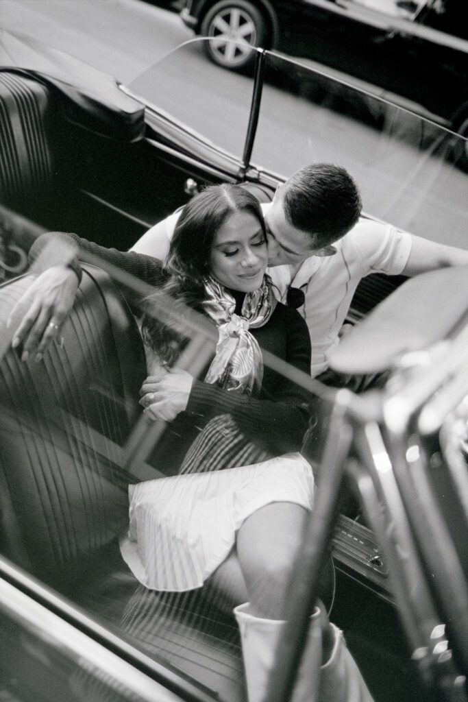 couple lounging and kissing in a parked convertible